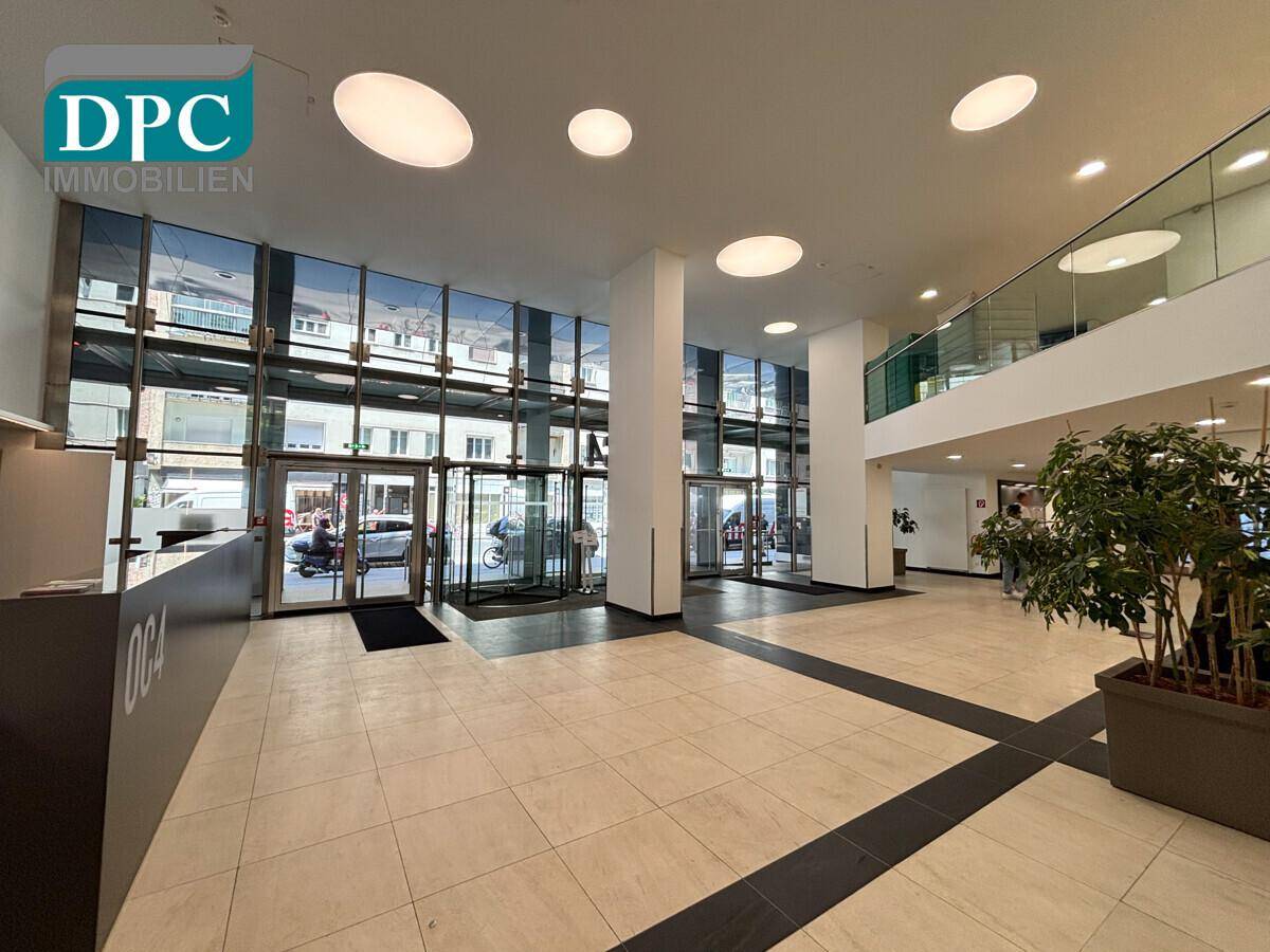 Geräumige, moderne Lobby mit Glasfassade, viel Tageslicht und einem eleganten Empfangsbereich.