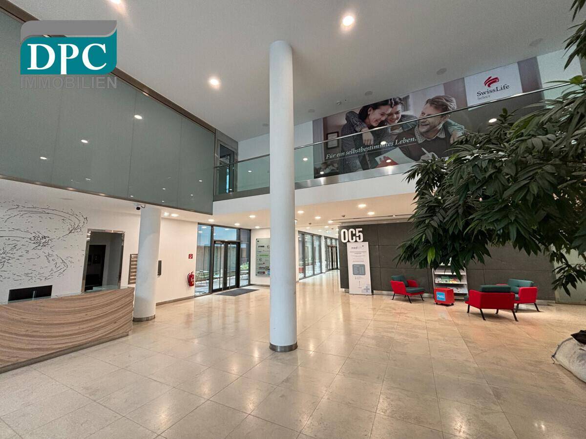 Helle und geräumige Lobby mit Steinboden, hohen Decken und einer modernen Rezeption.