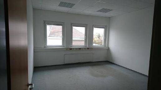 Leeres Büro mit drei Fenstern, Heizkörper und abgehängter Decke, bereit zur individuellen Gestaltung.