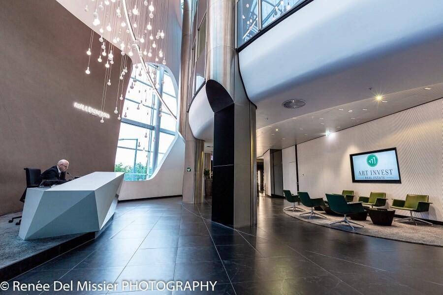 Elegante Lobby mit modernem Empfangstresen, Sitzgelegenheiten und künstlerischer Beleuchtung.