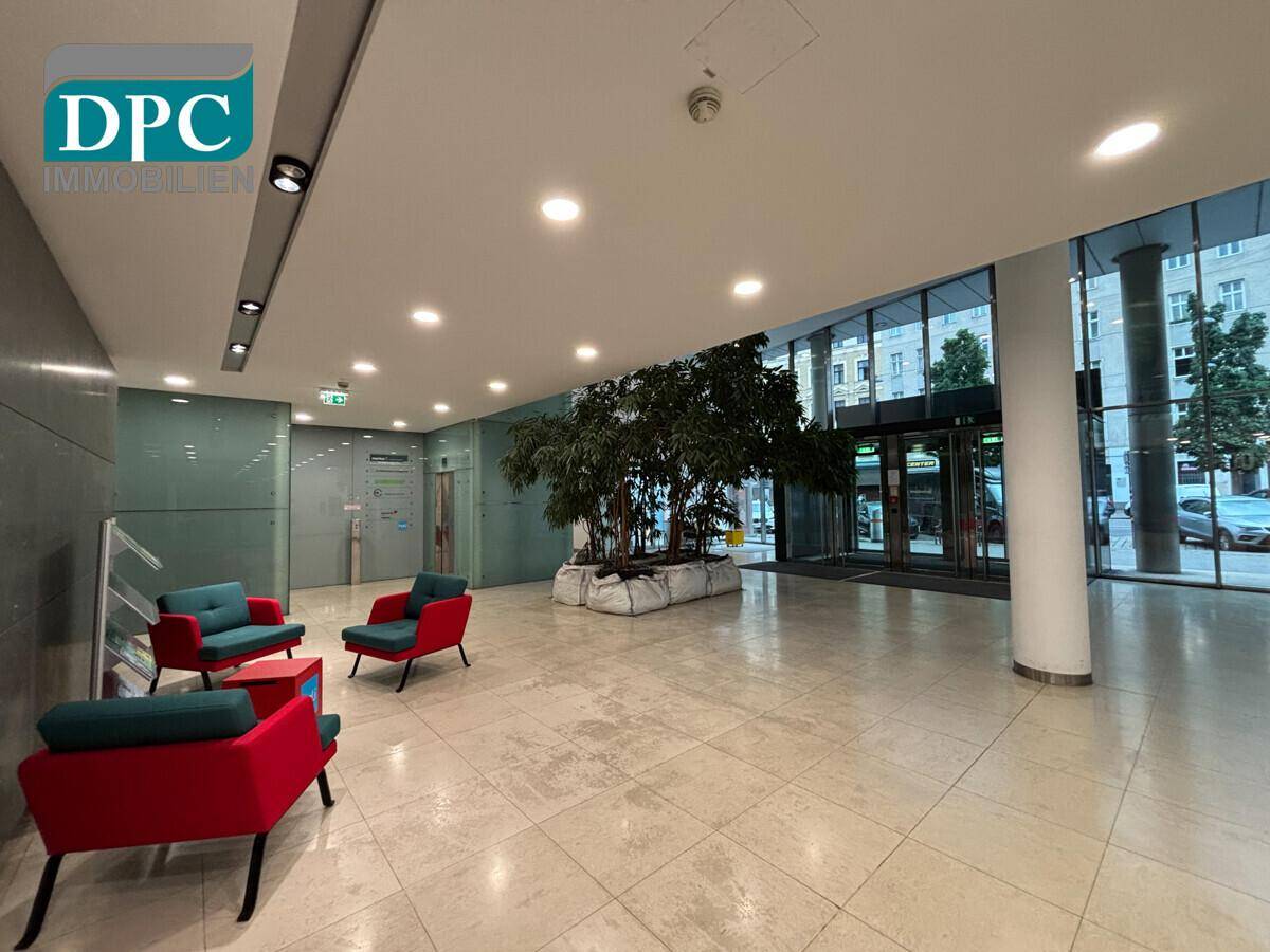 Elegante Lobby mit Steinboden, bequemen Sitzgelegenheiten und großen Fenstern zur Straße.