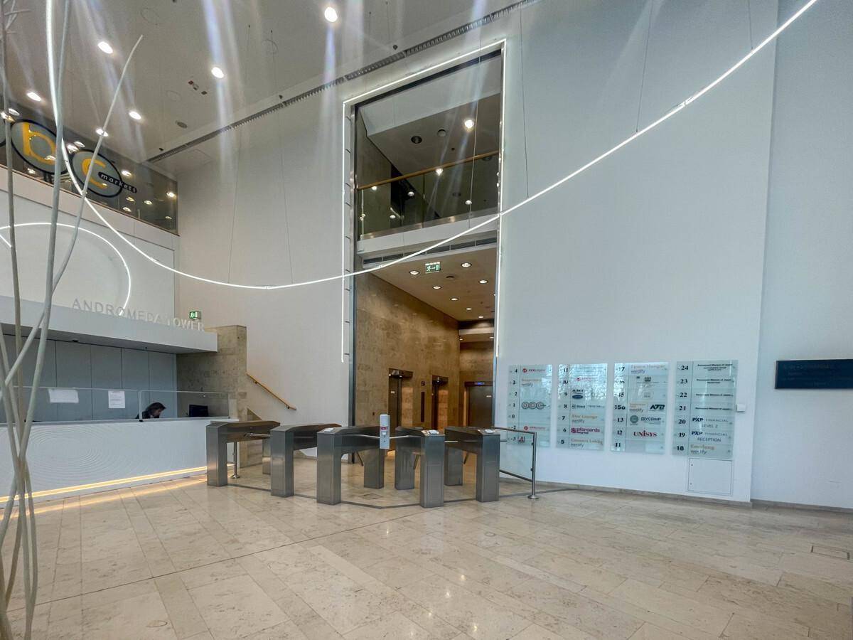 Moderne Lobby mit Sicherheitszugang, hohen Decken und Aufzügen im Hintergrund, die ein professionelles Ambiente schafft.