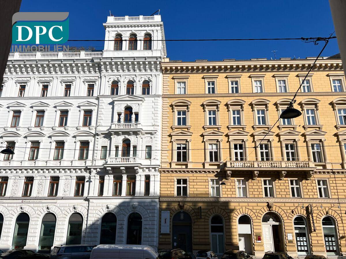 Historische Gebäude mit reich verzierten Fassaden in Weiß und Gelb unter blauem Himmel.
