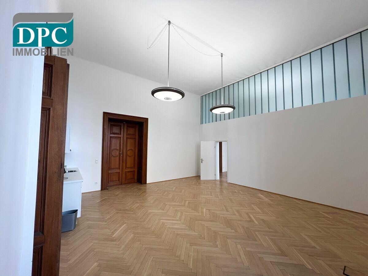 Großer, heller Raum mit Fischgrätparkett und einer Glasbausteinwand für zusätzliches Licht.