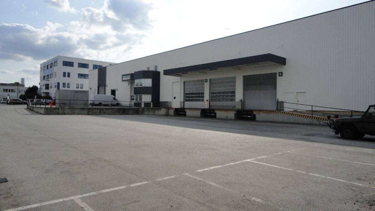 Großes Industriegebäude mit mehreren Laderampen und einem weitläufigen asphaltierten Vorplatz.