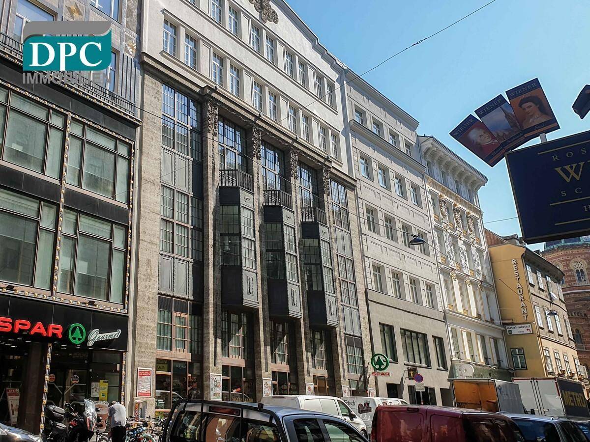 Historische Gebäudefassade mit Geschäften im Erdgeschoss und traditioneller Architektur in einer belebten Straße.