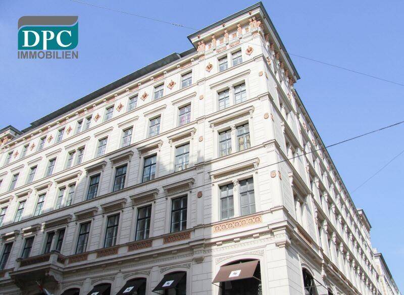 Detailansicht der historischen Eckfassade mit dekorativen Elementen und vielen Fenstern unter klarem Himmel.