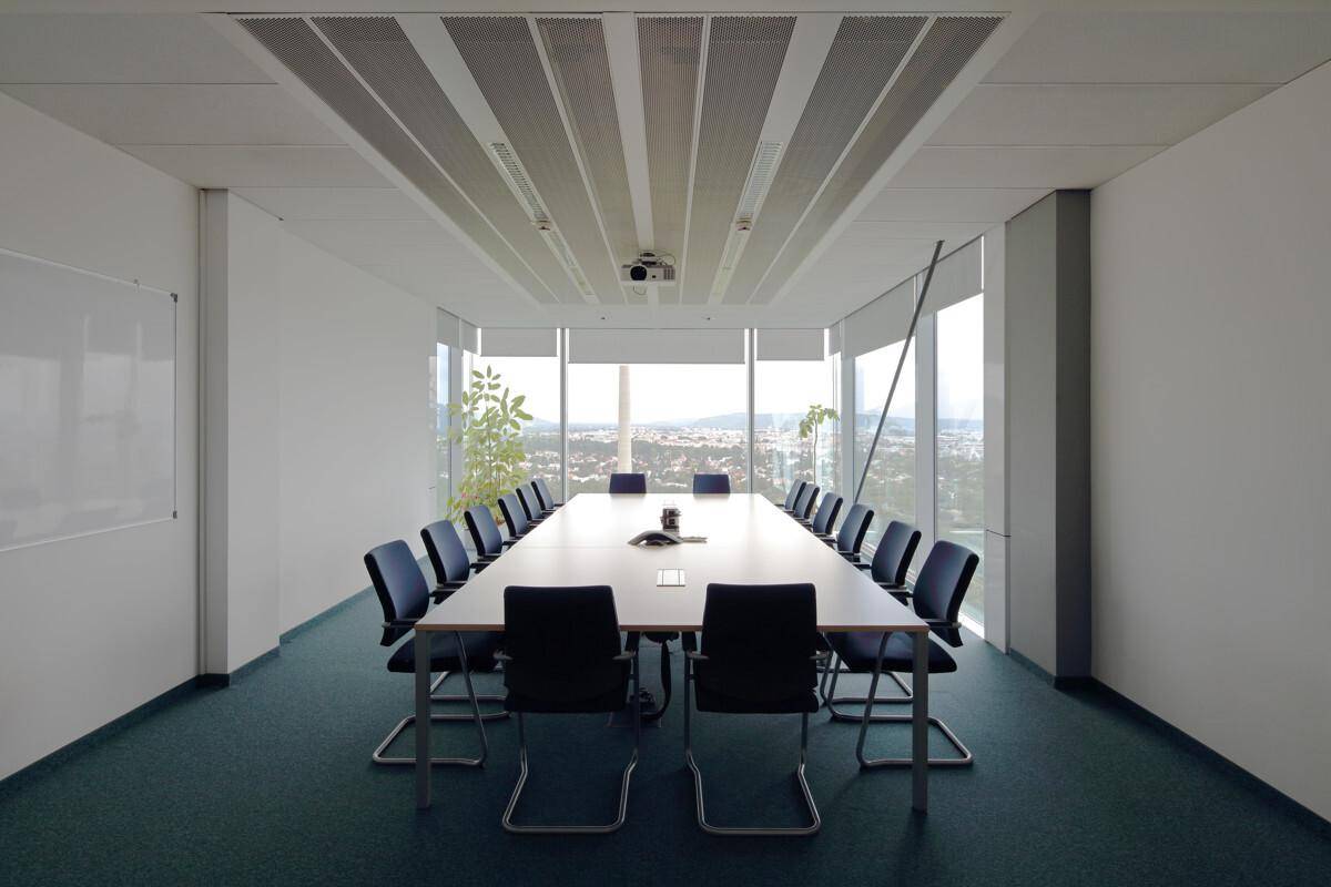 Großer Konferenzraum mit langem Tisch, vielen Stühlen und Panoramablick auf die Stadt und Landschaft.