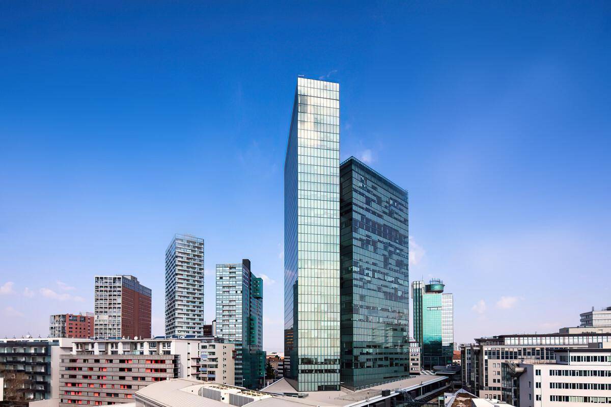 Beeindruckende Skyline mit modernen Hochhäusern und Glasfassaden unter klarem blauem Himmel.