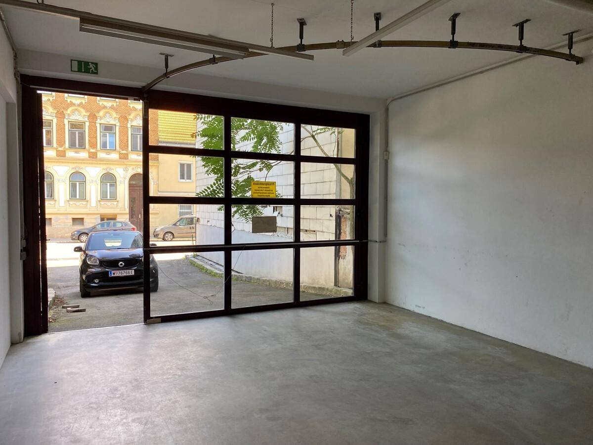 Innenansicht einer Garage mit großem Glasrolltor, das den Blick auf die Straße freigibt.