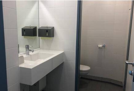 Modernes Badezimmer mit schwebendem Waschbecken, großem Spiegel und separater Toilettenkabine.
