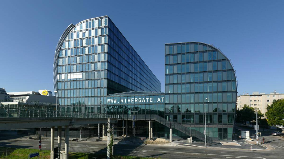 Weitläufige Ansicht eines modernen Bürokomplexes mit geschwungener Glasfassade und einem Werbebanner.