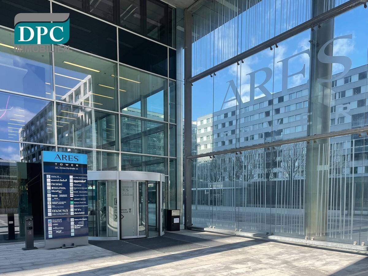 Eingangsbereich eines modernen Bürogebäudes mit großer Glasfront und Drehkreuz, das den Zugang zum Gebäude markiert.