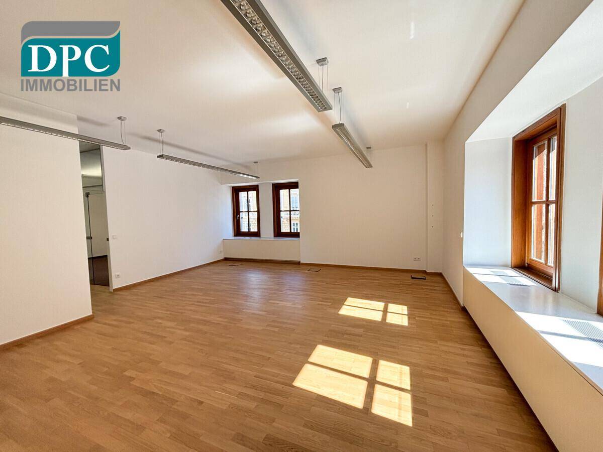 Heller Büroraum mit Holzboden und hohen Decken, bereit zur individuellen Gestaltung.