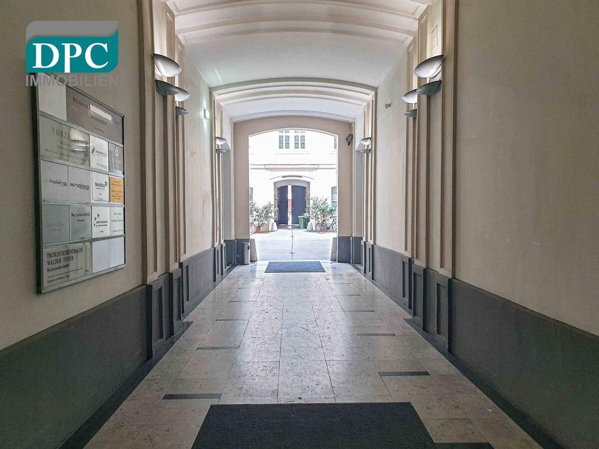 Langer, heller Eingangsbereich mit Marmorboden und gewölbter Decke, der zu einem Innenhof führt.