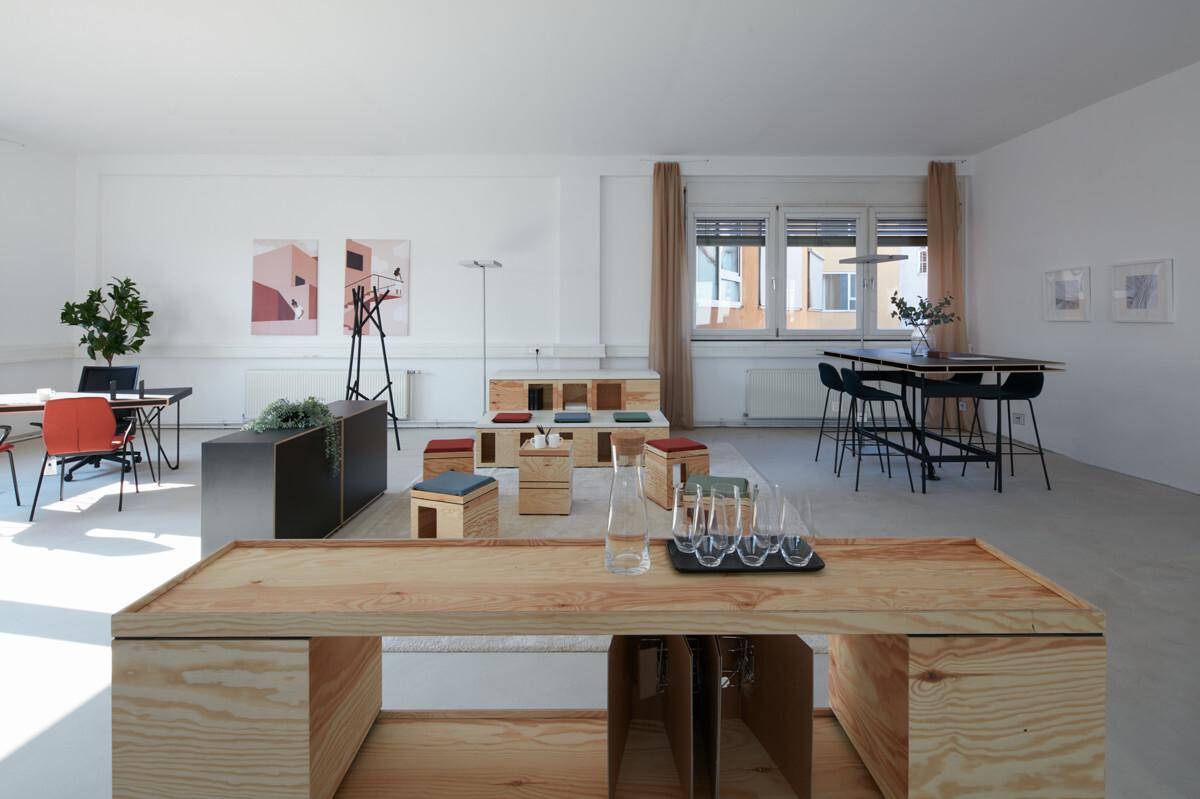 Heller Bürobereich mit flexiblen Holzelementen, modernen Kunstwerken und großen Fenstern für viel Tageslicht.