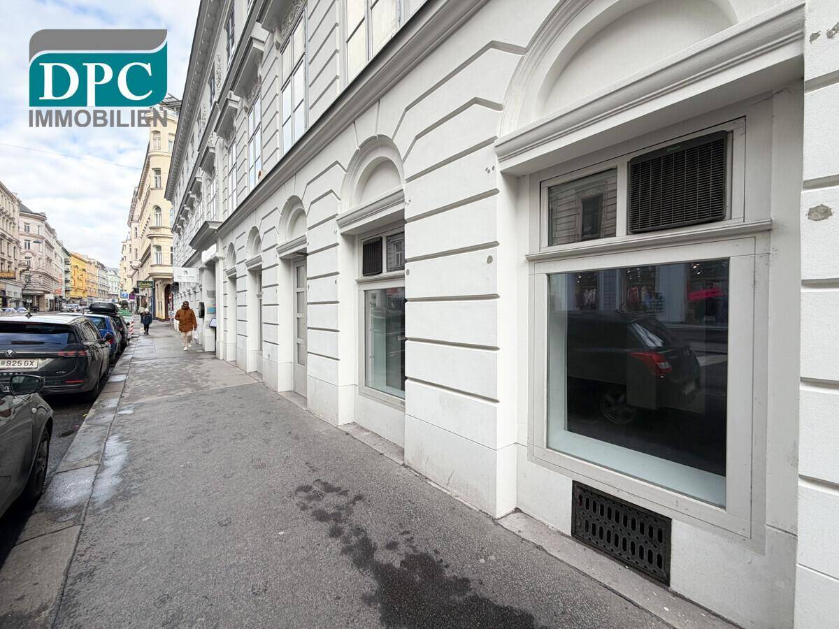 Außenansicht eines Gebäudes mit mehreren Geschäftsfenstern und klassischer Fassadengestaltung an einer Straße.