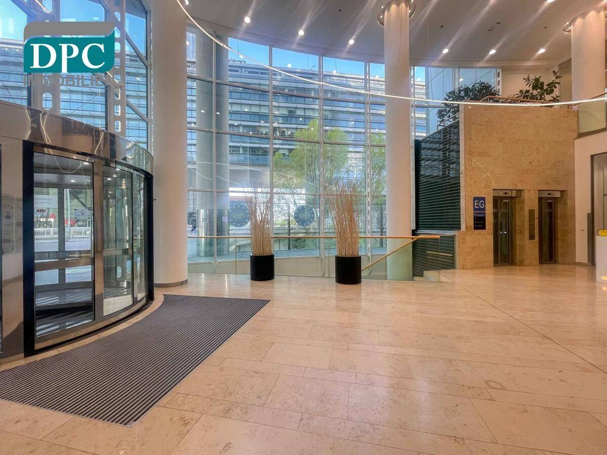 Eindrucksvolle, moderne Lobby mit hohen Decken, Marmorboden, Glasfassade und Aufzügen.