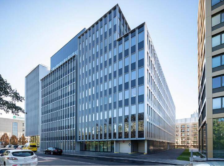 Architektonisch ansprechendes Bürogebäude mit reflektierenden Glasflächen und klaren Linien unter blauem Himmel.
