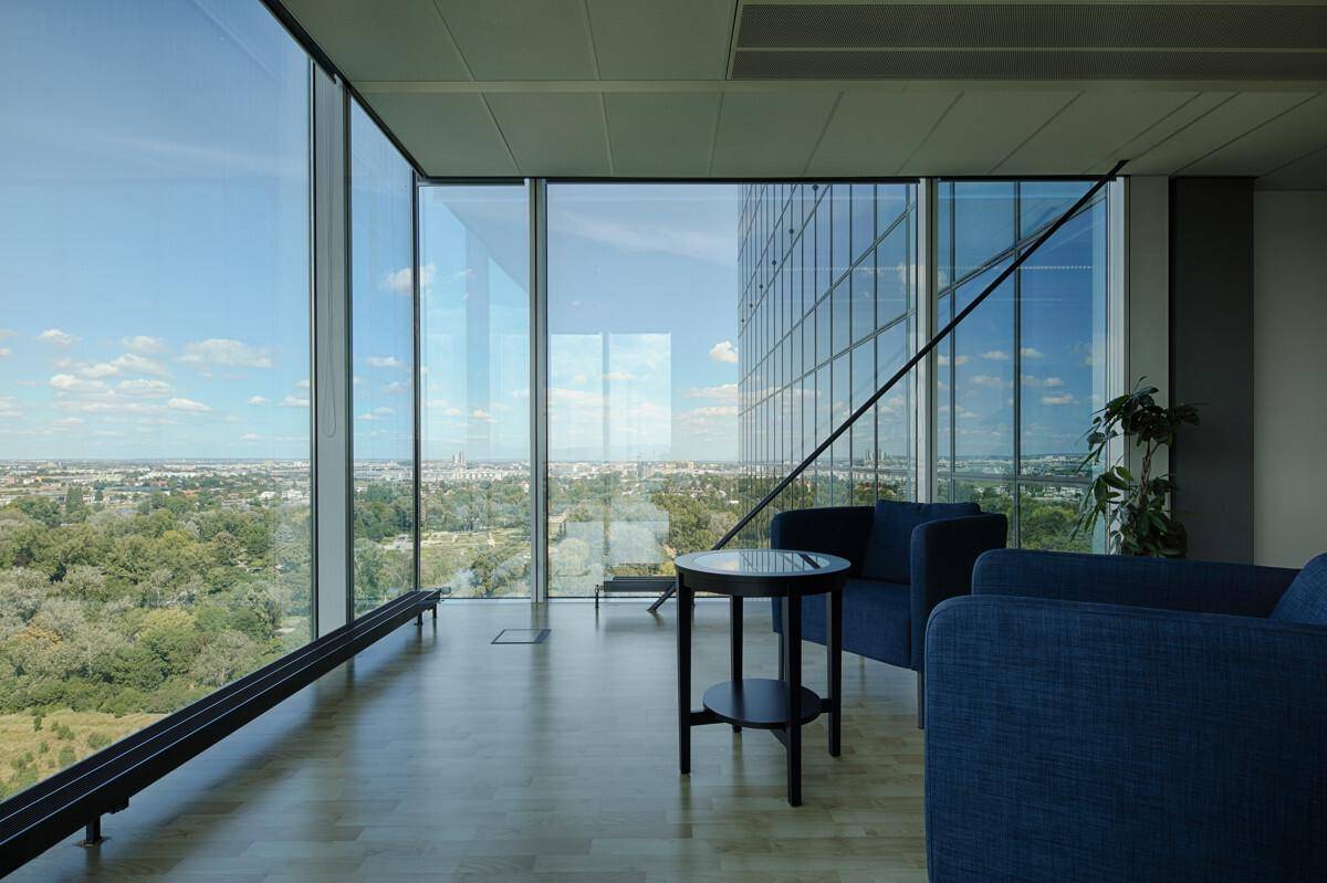 Gemütlicher Bürobereich mit blauen Sesseln, kleinem Tisch und raumhohen Fenstern mit weitem Blick.