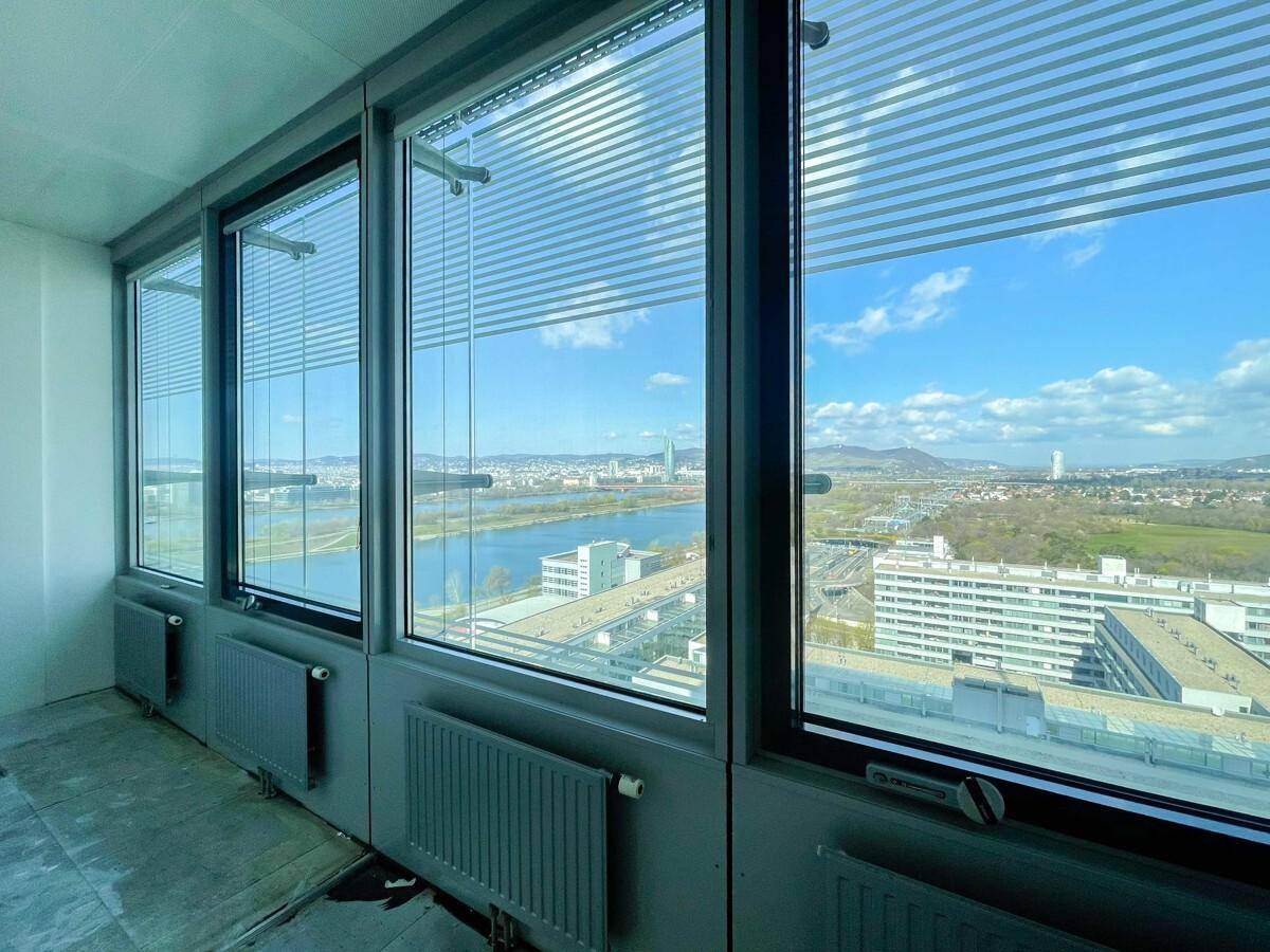 Innenansicht eines Büros mit großen Fenstern, die einen weiten Blick auf die Stadt und den Fluss bieten.