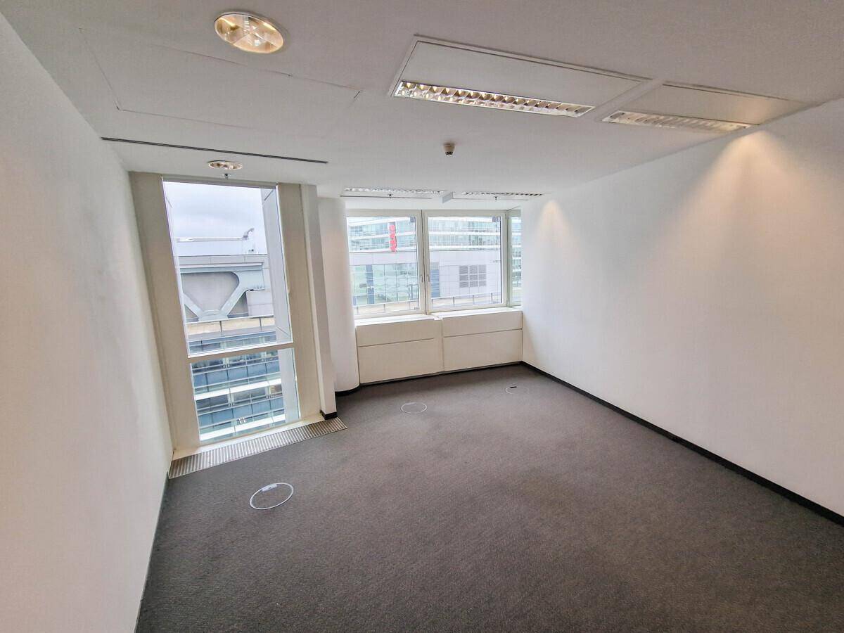 Kleineres Büro mit Teppichboden und Fenstern, die Tageslicht hereinlassen und einen Ausblick bieten.