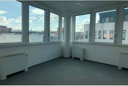 Helle Büroecke mit vielen Fenstern, Heizkörpern und einem weiten Blick über die Stadtlandschaft.