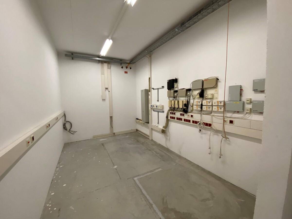 Kleiner Technikraum mit weißen Wänden, Betonboden und sichtbaren Elektroinstallationen.