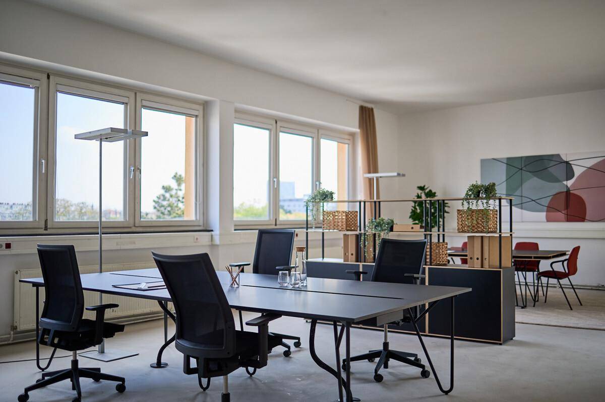 Heller Besprechungsbereich mit großen Fenstern, modernen Bürostühlen und einem langen Konferenztisch.