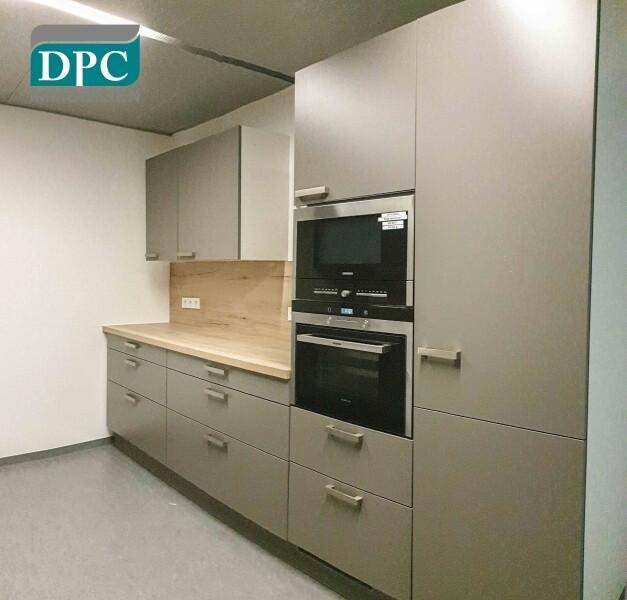 Moderne Küche mit grauen Schränken, Backofen und Mikrowelle in Hochschrank.