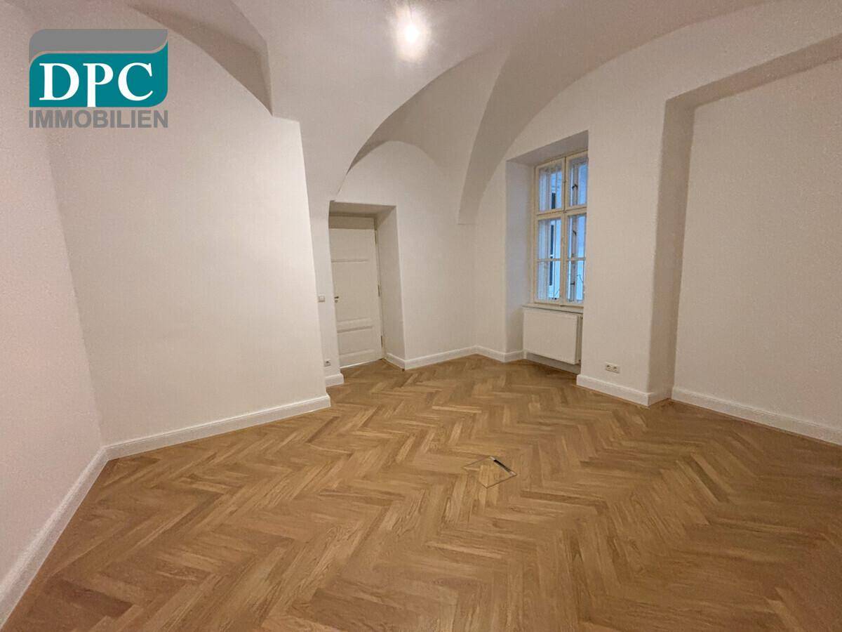 Zimmer mit einzigartiger Gewölbedecke, Fischgrätparkett und einem Fenster, das viel Tageslicht spendet.