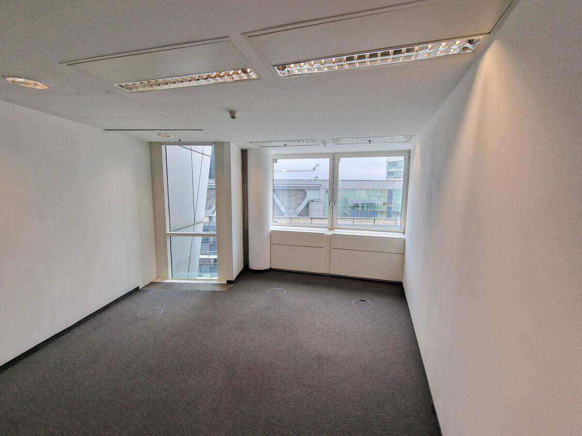 Kompaktes Büro mit Teppichboden und Fenstern, die eine helle und funktionale Arbeitsumgebung schaffen.