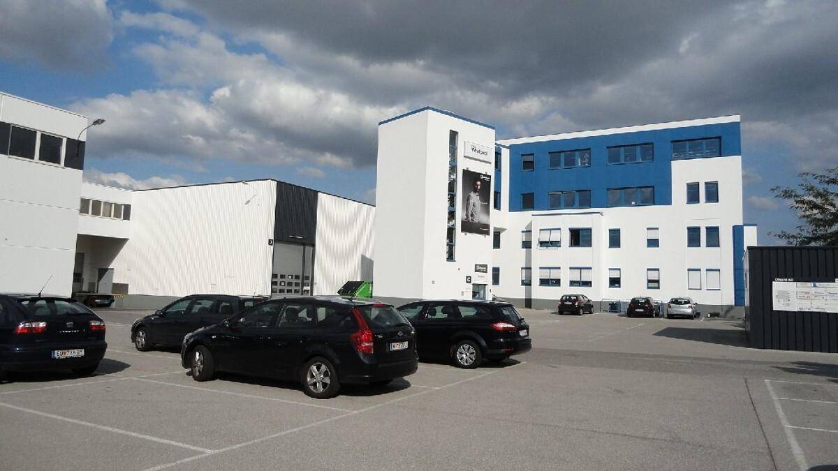 Ansicht eines Gewerbegebiets mit modernen Gebäuden und einem großen Parkplatz für Fahrzeuge.