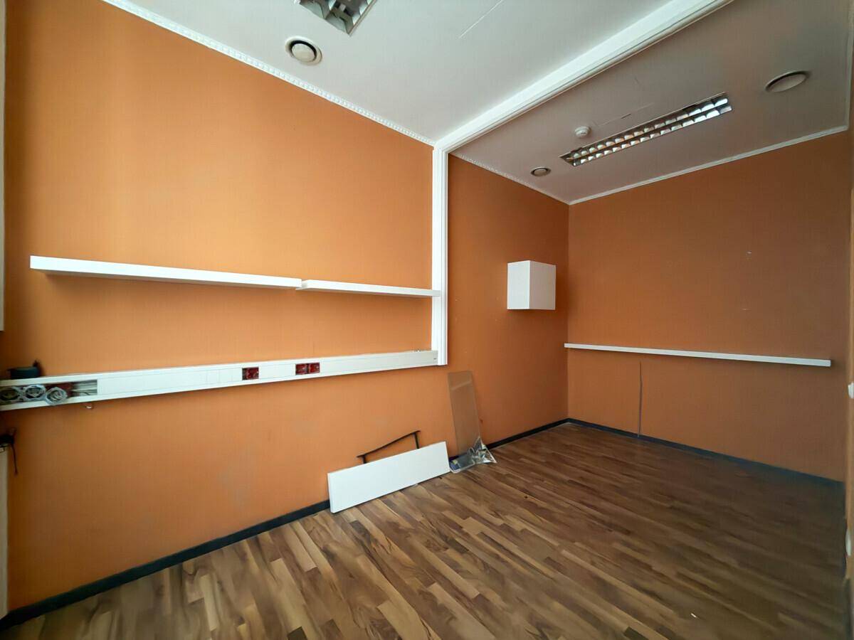 Kleiner Büroraum mit orangefarbenen Wänden, Holzboden und praktischen weißen Regalen.