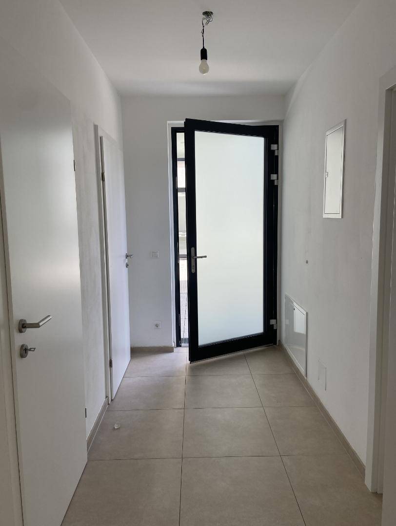 Heller Eingangsbereich mit Fliesenboden und moderner Eingangstür.