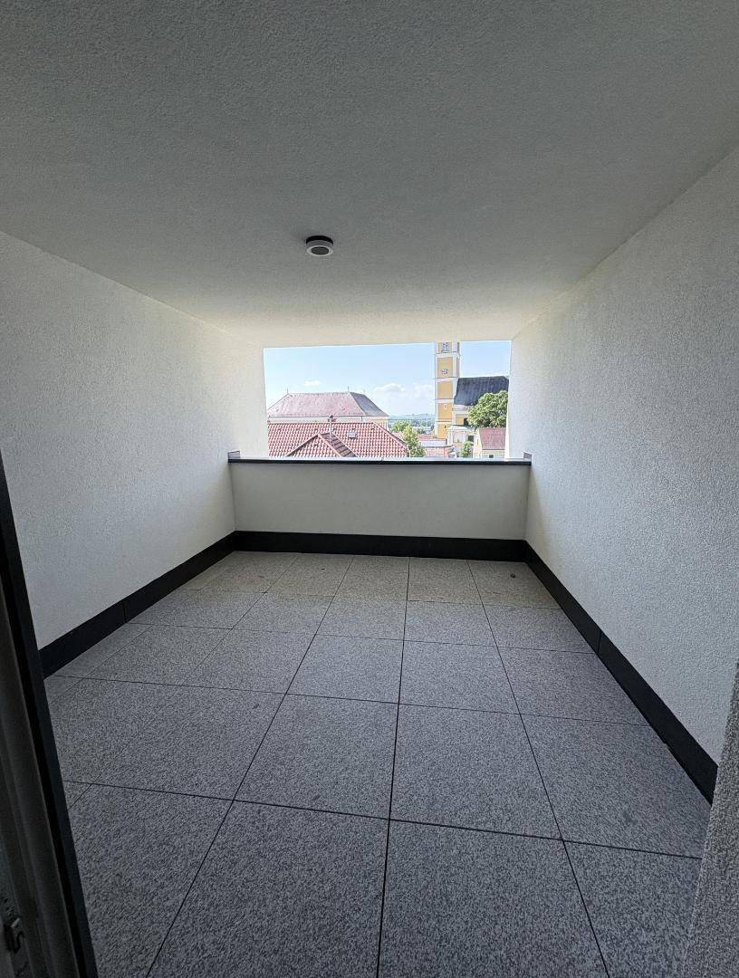 Überdachte Loggia mit Fliesenboden und weitem Blick auf die Umgebung.