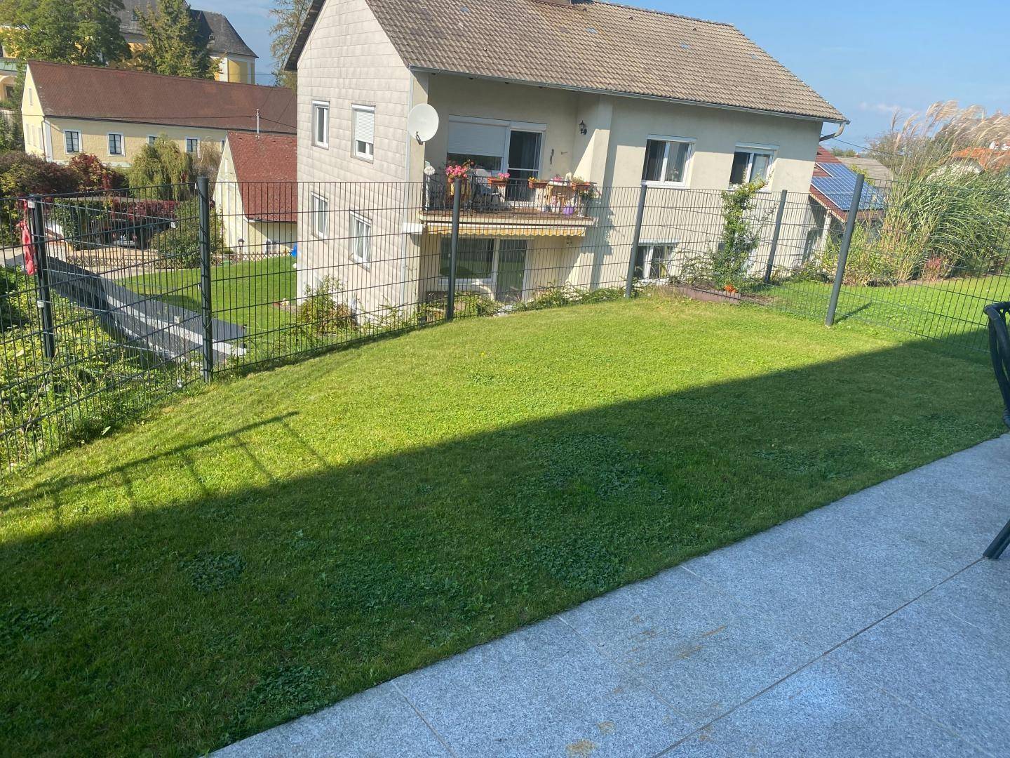 Gepflegter Gartenbereich mit Rasenfläche und Terrasse vor dem Wohnhaus.