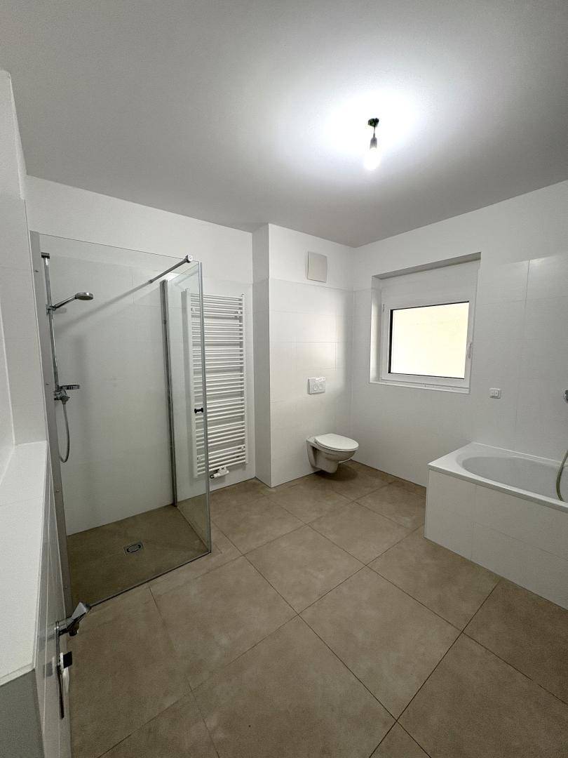 Geräumiges Badezimmer mit Dusche, Badewanne, WC und beheiztem Handtuchhalter.