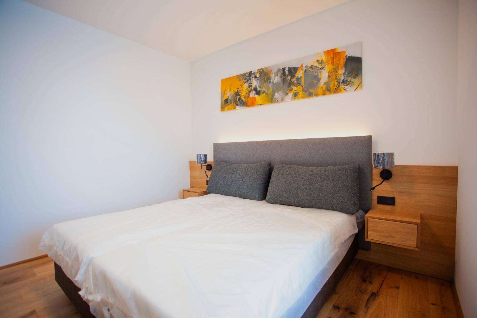 Helles Schlafzimmer mit Doppelbett, Holzelementen und moderner Kunst an der Wand.