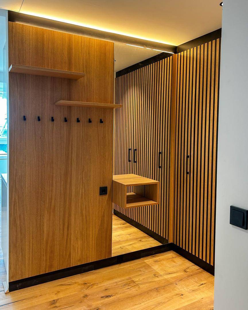 Moderner Flur mit Holzvertäfelung, Garderobe und großem Spiegel.