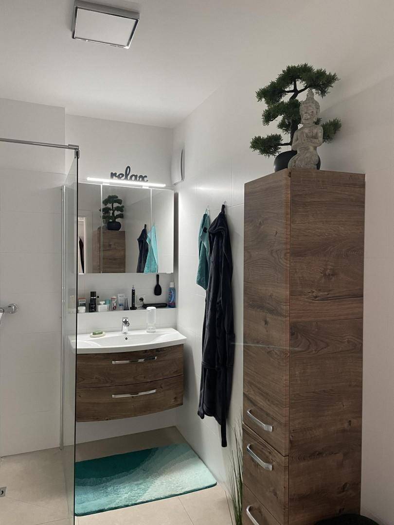 Modernes Badezimmer mit Waschtisch, Spiegelschrank und begehbarer Dusche.