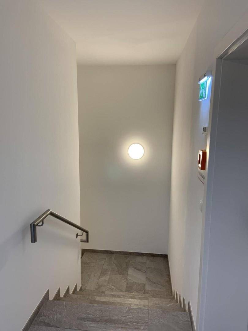 Heller Treppenaufgang mit Fliesenstufen und modernem Handlauf.