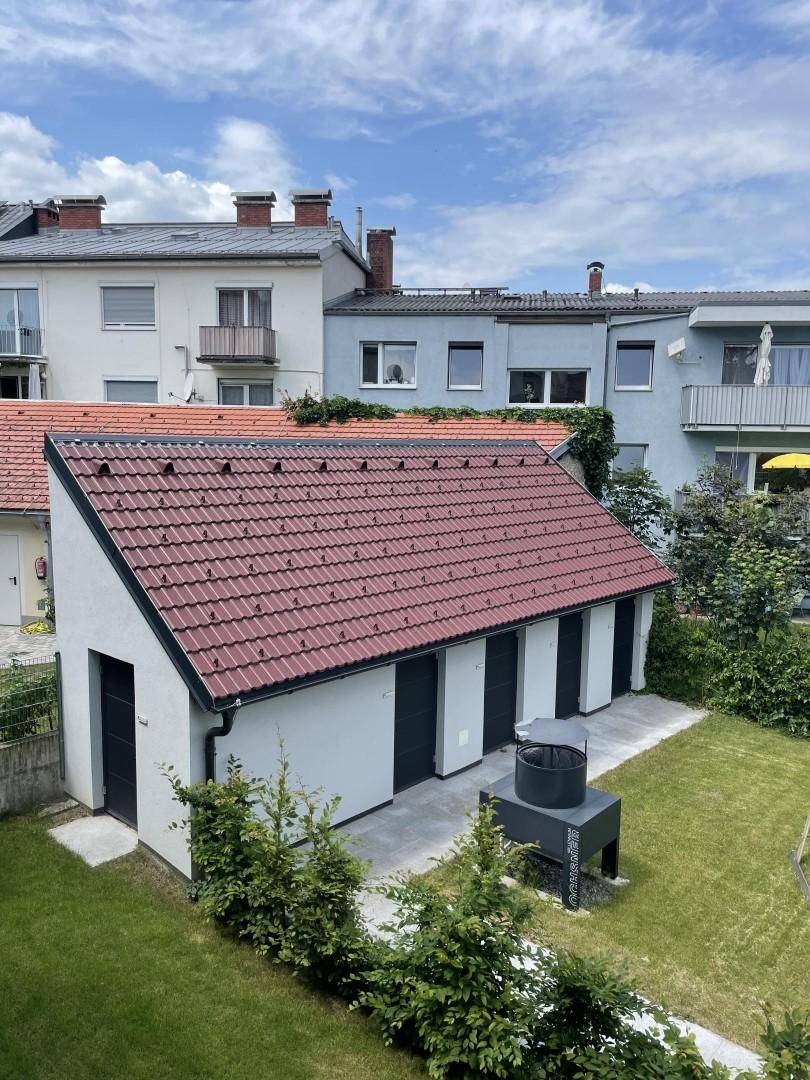 Nebengebäude mit mehreren Garagen und einem traditionellen Ziegeldach im Gartenbereich.