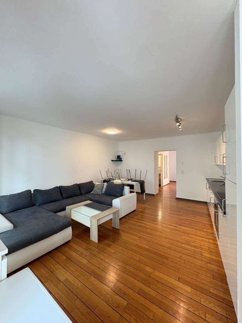 Geräumiger Wohn- und Essbereich mit Holzboden, großem Sofa und moderner Einrichtung.