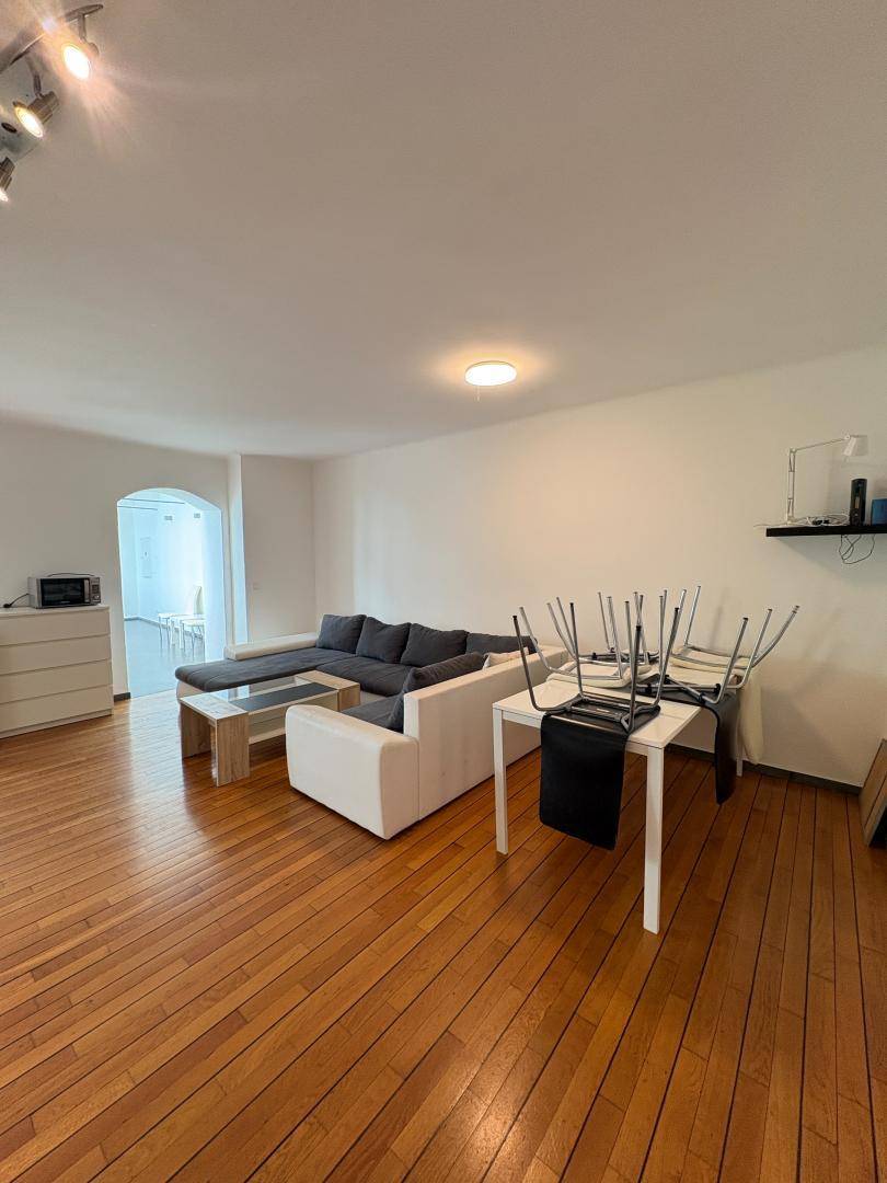 Heller Wohn- und Essbereich mit Holzboden, Sofa und Esstisch.