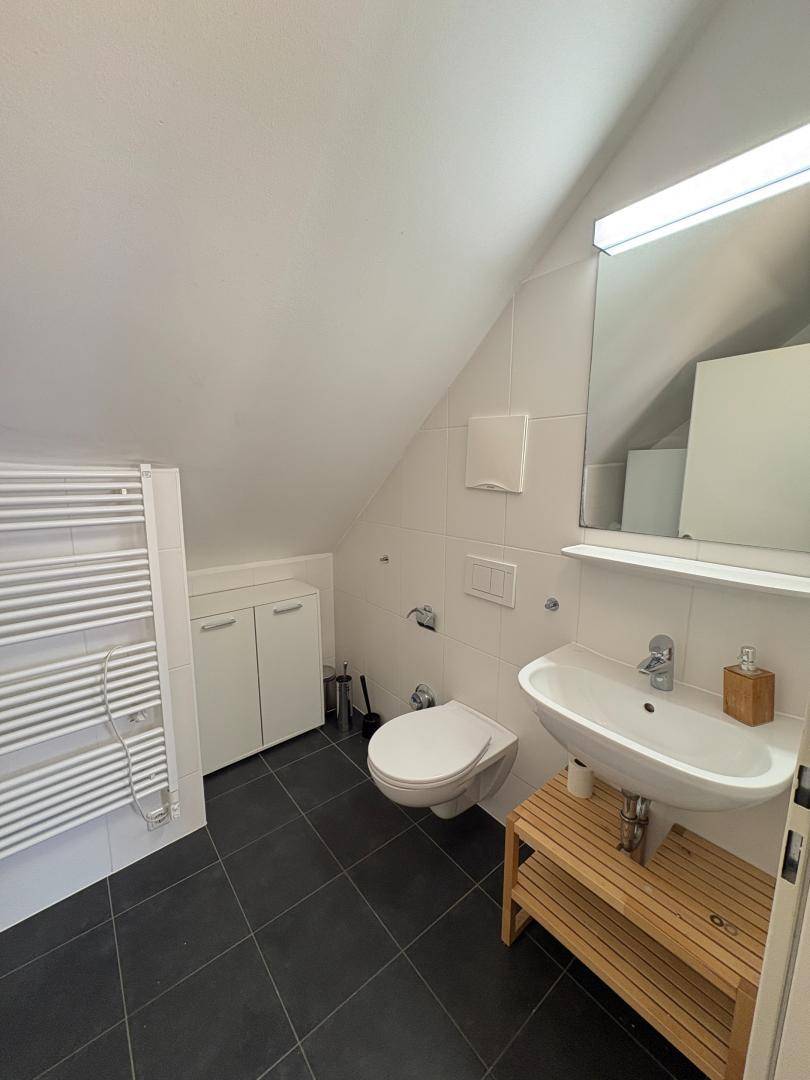 Modernes Badezimmer im Dachgeschoss mit Dusche, Waschbecken und beheiztem Handtuchhalter.