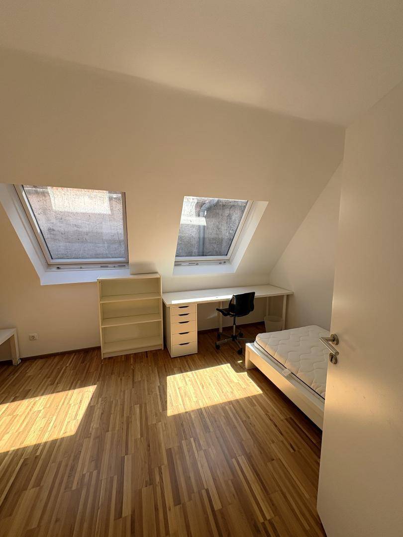 Dachgeschoss-Schlafzimmer mit Holzboden, Dachfenstern und viel natürlichem Licht.