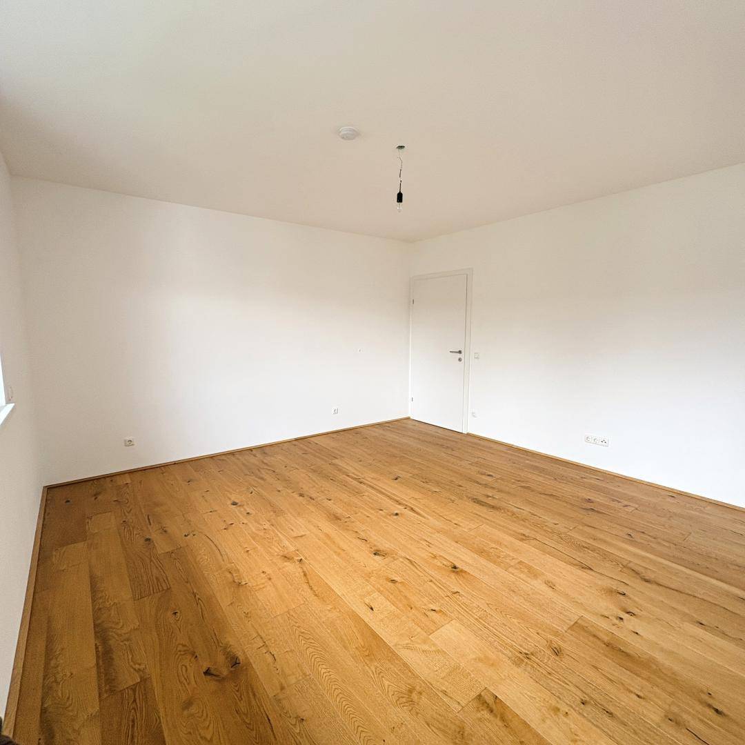 Geräumiges Schlafzimmer mit Holzboden und weiß gestrichenen Wänden, ideal für individuelle Gestaltung.