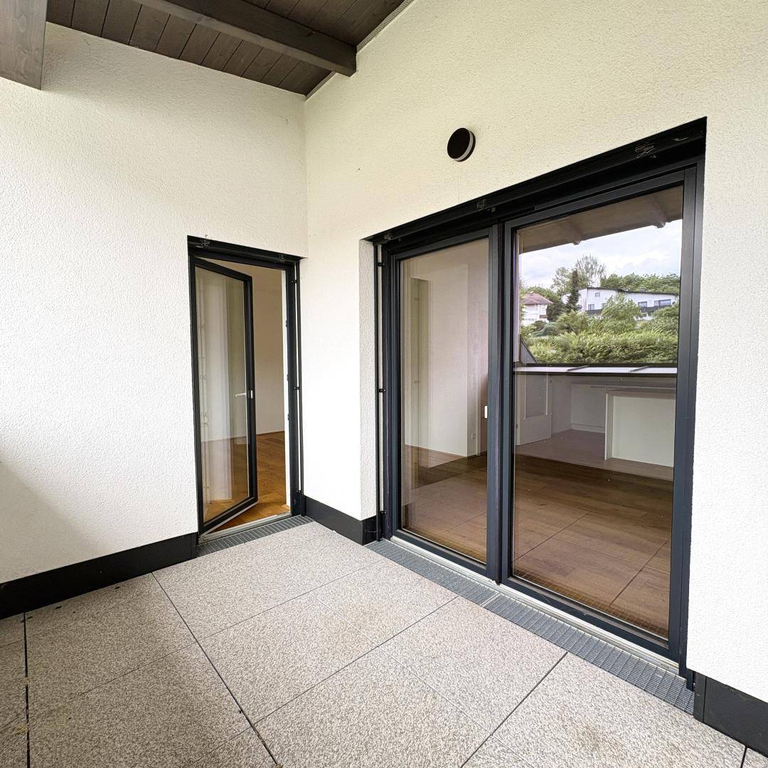 Überdachte Loggia mit Fliesenboden und Blick ins Grüne, ideal für entspannte Stunden im Freien.