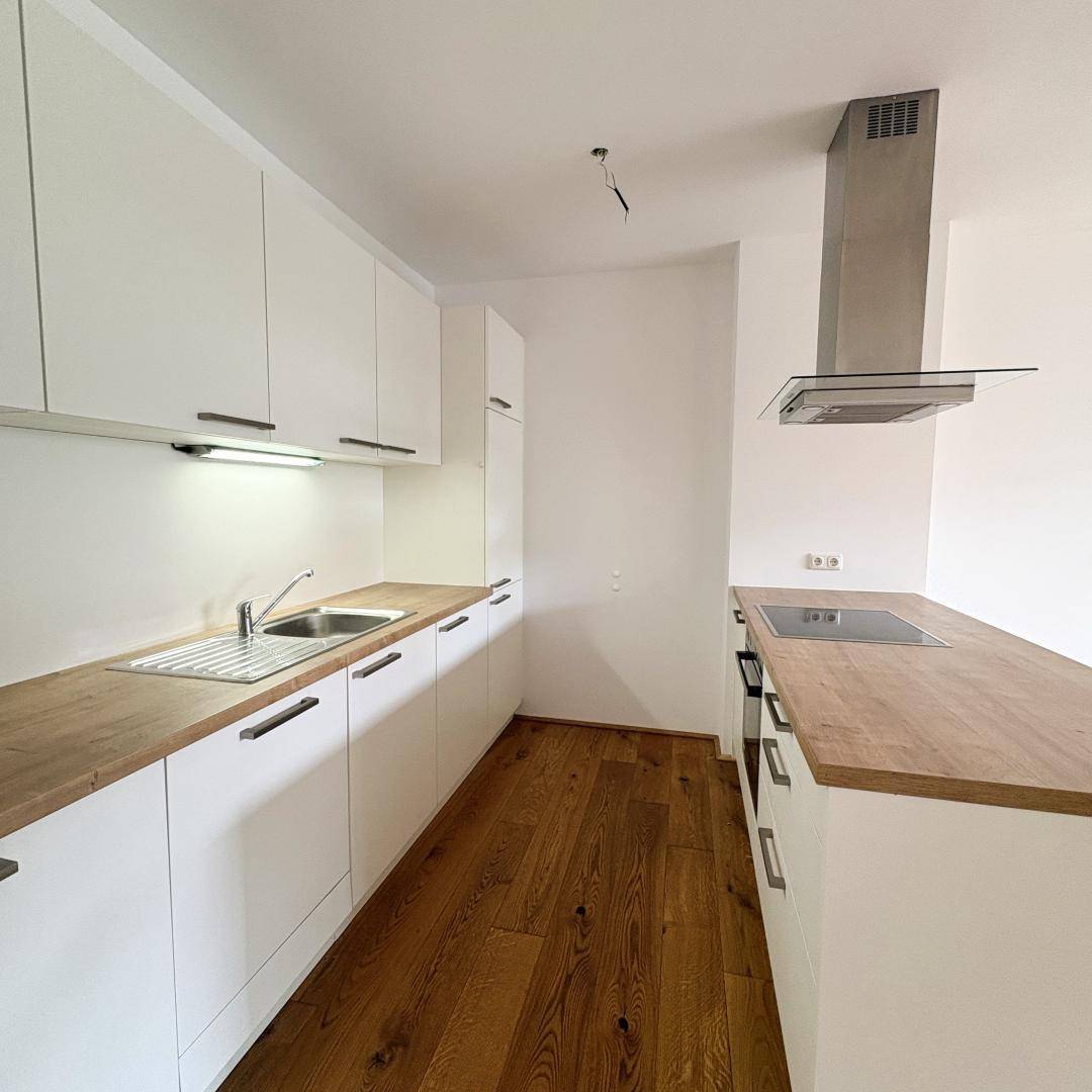 Funktionale, moderne Küche mit weißen Schränken, Holz-Arbeitsplatten und integrierten Geräten.